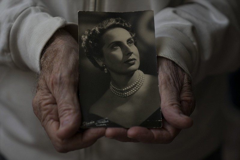 Sasha Weitman, son of Mimi Reinhard, a secretary in Oskar Schindler's office who typed up the list of Jews he saved from extermination by Nazi Germany, holds an old photograph of his mother in Herzliya, Israel, Monday, April 11, 2022. Mimi Reinhard died Friday in Israel at the age of 107. (AP Photo/Ariel Schalit)