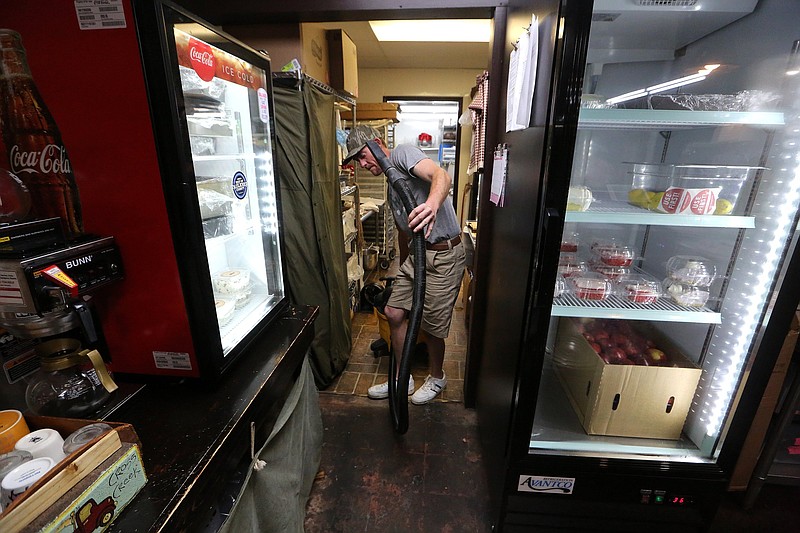 Derek Bailey, co-owner of Cross Creek Sandwich shop, pulls a wet-vac through the restaurant while vacuuming up flood damage after heavy rains on Monday night, April 11, 2022, in downtown Conway. Bailey said they got about two inches of water in the restaurant, but got it cleaned up and plan to be open on Tuesday. 
(Arkansas Democrat-Gazette/Thomas Metthe)