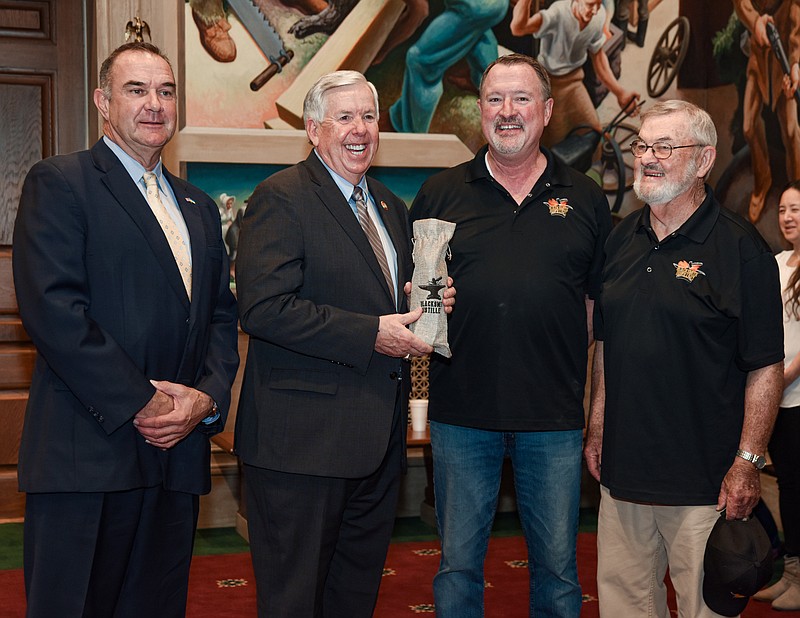 Julie Smith/News Tribune
Gov. Mike Parson, second from left, laughed after joking that he may have to break into the bottle he just received from Lt. Gov. Mike Kehoe, at left, on behalf of , Mike Broker, III and Mike Broker, Jr., at right,  the father-son team behind Blacksmith Distillery in Lohman. In celebration of the state's bicentennial in 2021, the distillery produced 200 bottles of bourbon, each one of which was numbered. As he is the 57th governor of Missouri, Parson was given bottle number 57 of 200 during the day's Buy Missouri festivities kickoff in the House of Representatives lounge.