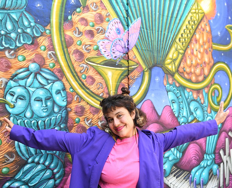Danaé Brissonnet stands in front of the mural she painted at SQZBX. - Photo by Tanner Newton of The Sentinel-Record