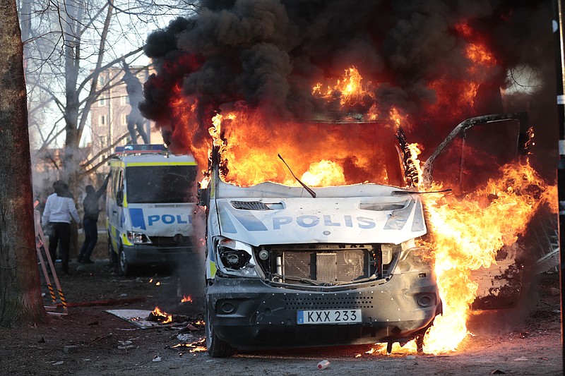 Protesters set fire to a police bus in the park Sveaparken in Orebro, Sweden, Friday, April 15, 2022. Police in Sweden say they are preparing for new violent clashes following riots that erupted between demonstrators and counter-protesters in the central city of Orebro on Friday ahead of an anti-Islam far-right group&#x2019;s plan to burn a Quran there. (Kicki Nilsson/TT via AP)