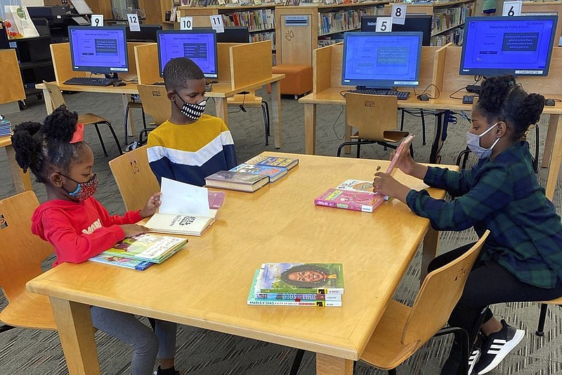 In this undated photo provided by Dalaine Bradley, Drew Waller, 7, Ahmad Waller, 11, and Zion Waller, 10, left to right, study at Cameron Village Library during homeschooling, in Raleigh, N.C. (Courtesy of Dalaine Bradley via AP)