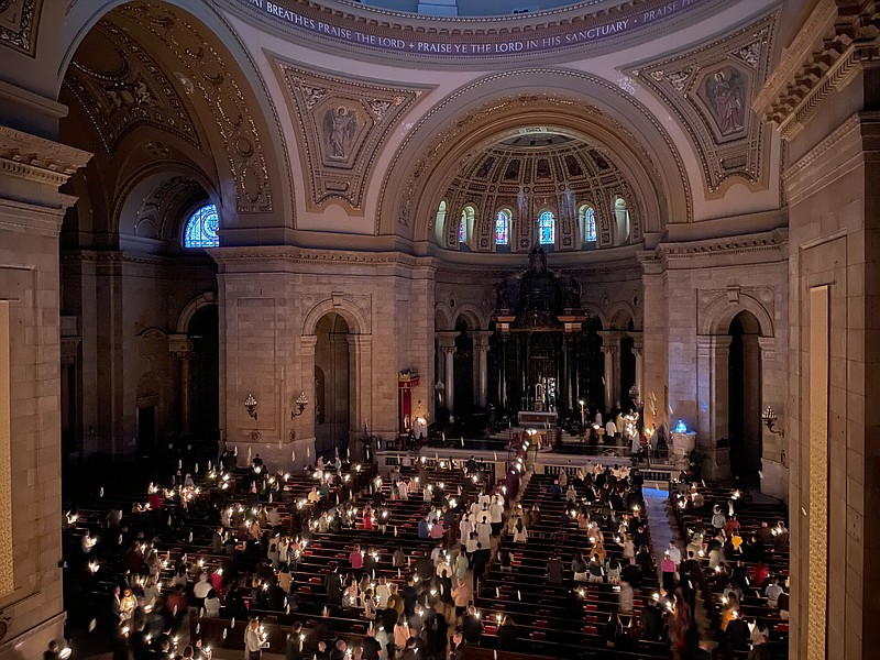 Hundreds of people light candles at the beginning of the Easter Vigil Mass at the Cathedral of St. Paul in St. Paul, Minn., on Saturday, April 16, 2022. For many U.S. Christians, this weekend marks the first time since 2019 that they will gather in person on Easter Sunday, a welcome chance to celebrate one of the year's holiest days side by side with fellow congregants. (AP Photo/Giovanna Dell'Orto)