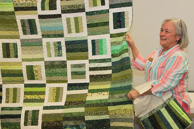 Jackie Bibbs of Benton shows off a quilt she made from "scraps." She's a member of the Arkansas Quilt Guild, which meets at the North Little Rock Community Center. The quilt will be one of more than 20 that guild members plan to make and donate to charity. Using scraps, she said, helps reduce the size of her stash of fabrics.
(Special to the Democrat-Gazette/Frank Fellone)