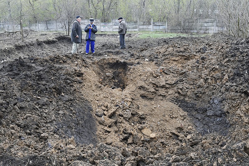 Men stands next to a crater of an explosion after night shelling in Kramatorsk, Ukraine, Monday, April 18, 2022. (AP Photo/Andriy Andriyenko)