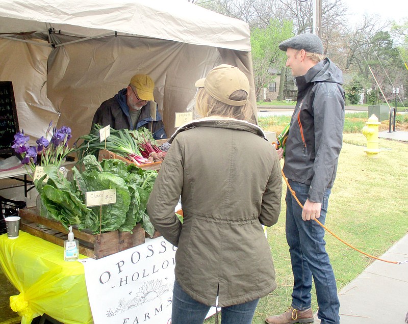 Marc Hayot/Herald-Leader Tom Fairbanks (left), of Opossum Hollow Farms wraps up produce for Kelsey Howard and her husband Jordan during the opening of the Farmers Market on Saturday. Opossum Hollow Farms has been a 10 year staple at the Farmer's Market.