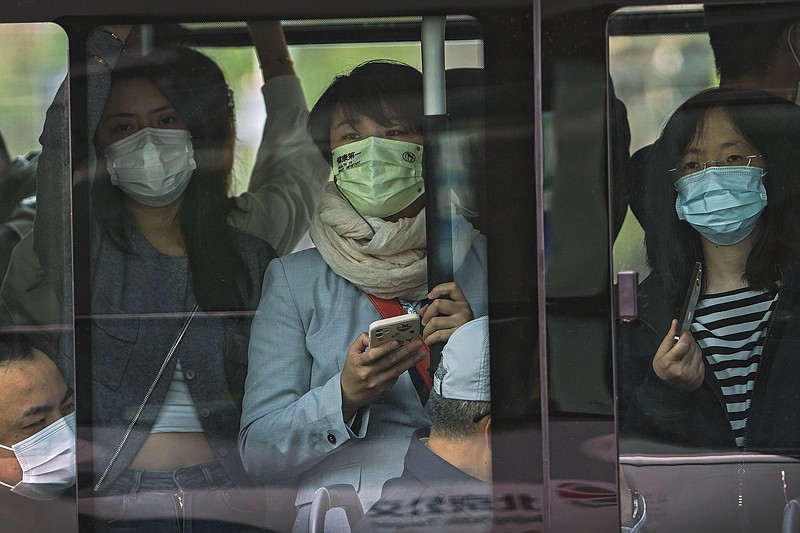 Commuters wearing face masks to help protect from the coronavirus look out from a crowded traveling bus during the morning rush hour, Monday, April 18, 2022, in Beijing. (AP Photo/Andy Wong)