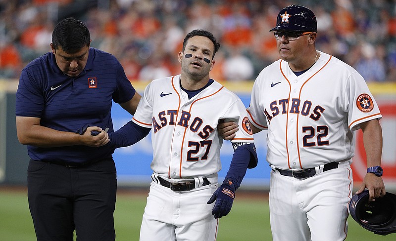 Houston Astros' Jose Altuve, center, is helped off the field after legging out an infield single in the bottom of the eighth inning against the Los Angeles Angels, Monday, April 18, 2022, in Houston. (Kevin M. Cox/The Galveston County Daily News via AP)