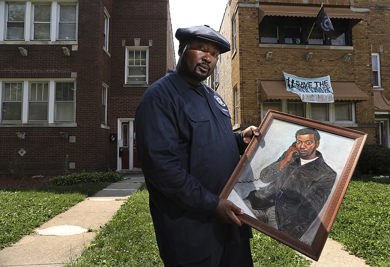 Chairman Fred Hampton Jr. holds a painting of his father Fred Hampton outside his family home in the Maywood suburb of Chicago, Thursday, July 25, 2019. The painting of Fred Hampton shows him as a 20 year-old talking on a phone at his office, one year before he was killed by police. The suburban Chicago home where slain Black Panther Party leader Fred Hampton grew up has been designated a historical landmark by the village of Maywood.  (Antonio Perez/Chicago Tribune via AP)