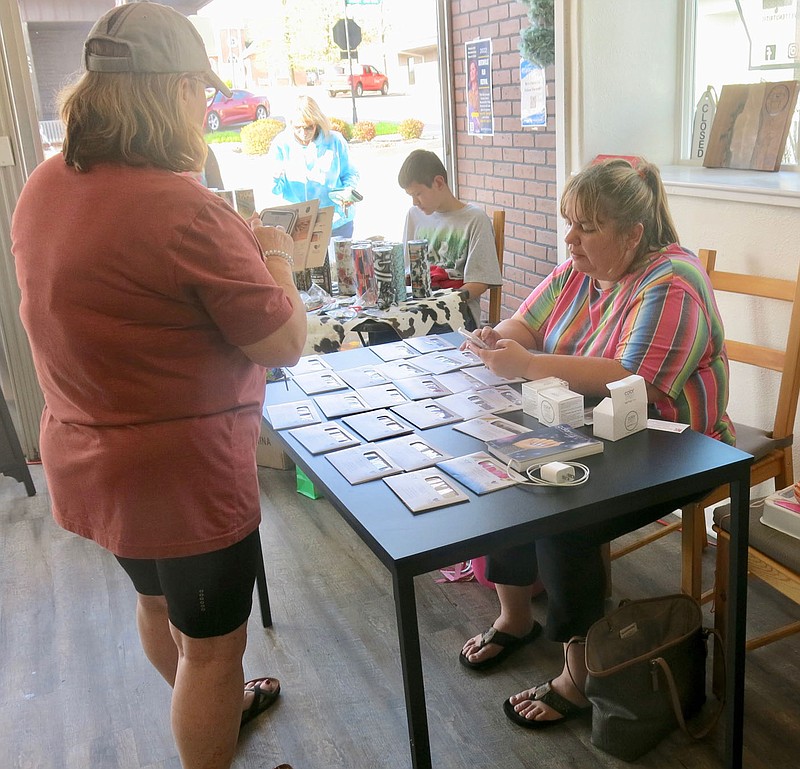 Westside Eagle Observer/SUSAN HOLLAND
Tina Crose (right) shows a customer some of the wide variety of Color Strip nail covers available at her booth during Third Thursday on Main events April 21 in Gravette. Tina and other vendors set up booths in the Gravette Nutrition building and offered products to visitors at the evening's activities.