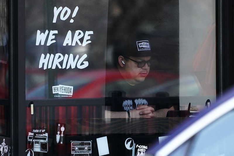 A hiring sign is displayed at a restaurant in Schaumburg, Ill., Friday, April 1, 2022. Despite the inflation surge, persistent supply bottlenecks, damage from COVID-19 and now a war in Europe, employers have added at least 400,000 jobs for 11 straight months. (AP Photo/Nam Y. Huh)