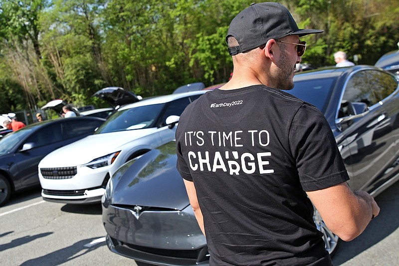 Francesco Guarnieri, right, wears a shirt celebrating Earth Day near a display of electric vehicles lined up in a parking lot across from the Little Rock Zoo as part of the facility's Earth Day events Saturday, April 23, 2022. (Arkansas Democrat-Gazette/Colin Murphey)