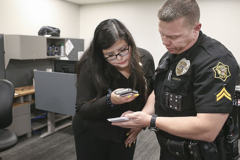 UA social work student Eugenia Franco (left) receives notes Friday about a client from Cpl. Matthew Johnson of the Springdale Police Department at the department in Springdale. The Springdale Police Department is working with two UA social work students to help them on calls, freeing officers to return to patrol. Check out nwaonline.com/220424Daily/ and nwadg.com/photos for a photo gallery.
(NWA Democrat-Gazette/Charlie Kaijo)
