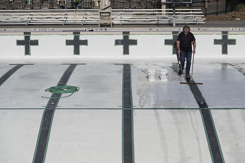 Pat Benton works to dry out a pool at the Rogers Aquatic Center Friday, April 22, 2022 before working to paint it. The city of Rogers says its aquatics center could be impacted by a lack of lifeguards. City has taken some steps to try to make the job more enticing. (NWA Democrat-Gazette/Spencer Tirey)