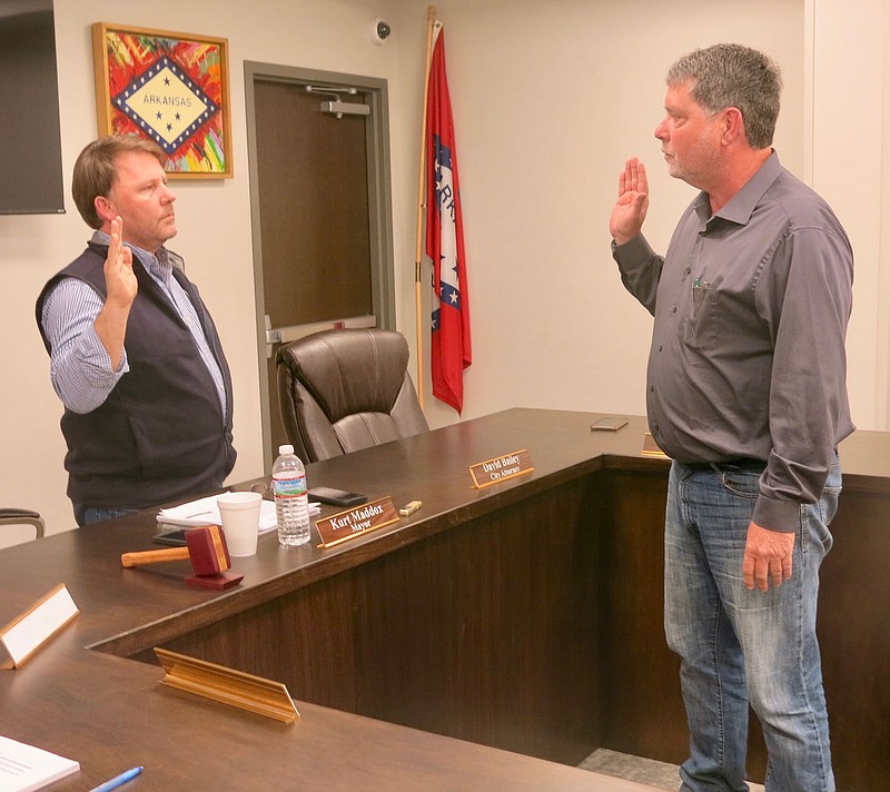 Westside Eagle Observer/SUSAN HOLLAND
Mayor Kurt Maddox administers the oath of office to Mike Dennison, new member of the Gravette city council. Dennison, who was sworn in at the April 28 council meeting, will fill the ward 1, position 1 seat vacated by Ron Theis, who moved out of town.