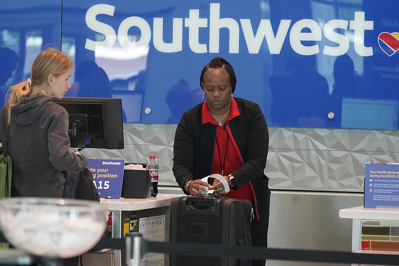 A Southwest Airlines ticket agent tags a bag for a traveler at Love Field in Dallas, Tuesday, April 19, 2022. The major airlines and many of the busiest airports dropped their requirements after a Florida judge struck down the CDC mandate and the Transportation Security Administration announced it wouldn't enforce its 2021 security directive. (AP Photo/LM Otero)