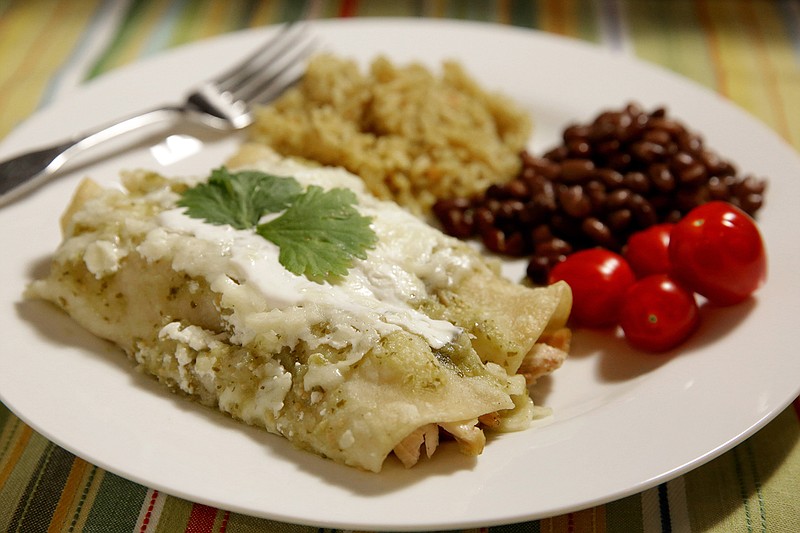Enchiladas Suizas with chicken, served alongside rice and beans and grape tomatoes. (St. Louis Post-Dispatch/TNS/Hillary Levin)