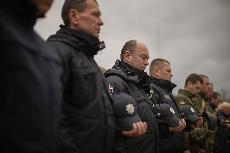 Decorated Ukrainian National Guard soldiers and State Emergency Service units' members observe a minute of silence during a ceremony commemorating the Chernobyl nuclear power plant disaster, at the Those Who Saved the World monument in Chernobyl, Ukraine, Tuesday, April 26, 2022. (AP Photo/Francisco Seco)