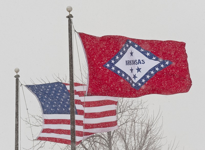 FILE - In this Feb. 1, 2011 file photo, an American and Arkansas flag blow in the wind as snow falls in Fayetteville, Ark.  (AP Photo/Beth Hall, File)