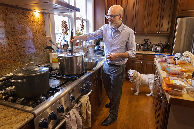 Frisbee watches as Daniel Promislow, PhD, with the Promislow Lab at the University of Washington, prepares food for his 16-year-old dog in the kitchen of his Seattle home Friday, March 11, 2022. Dr. Promislow is the principal investigator of the Dog Aging Project. He cooks chicken, sweet potatoes and oats and then freezes the food so Frisbee will have a healthy diet. Frisbee also eats kibbled food mixed with water, a bit of seaweed for iodine, multivitamins and probiotics. (Ellen M. Banner/The Seattle Times/TNS)