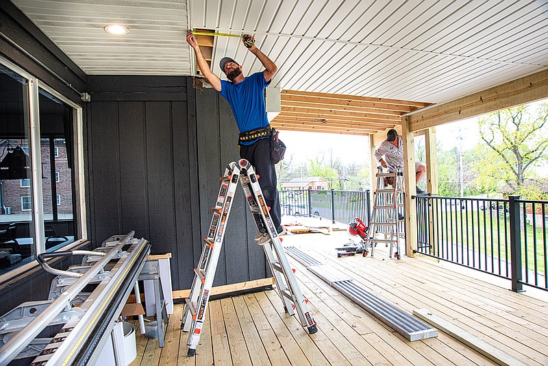 Gary Geick and Justin Lueckenhoff, of Gerlach Construction, work Thursday on the covered portion of the new deck at The Pizza Company on East McCarty Street. (Julie Smith/News Tribune)