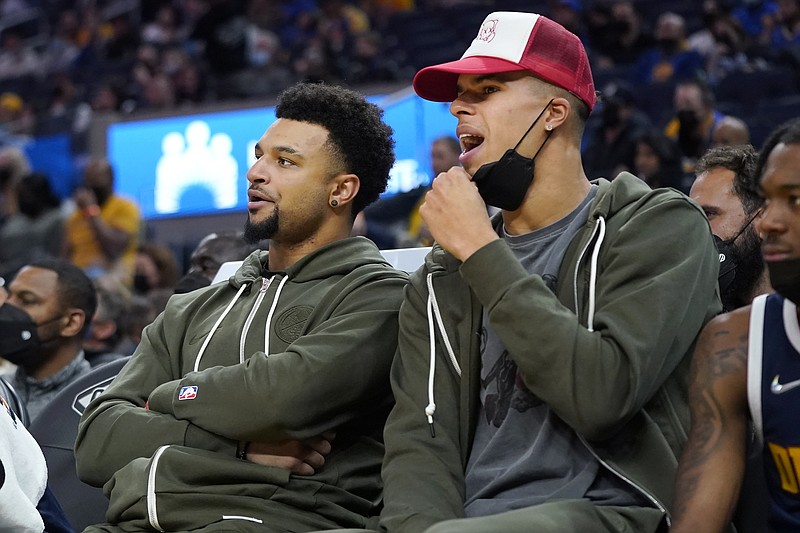 FILE - Denver Nuggets' Jamal Murray, left, and Michael Porter Jr. watch from the bench during the first half of a preseason NBA basketball game against the Golden State Warriors in San Francisco, Oct. 6, 2021. The Nuggets sorely missed point guard Murray (ACL recovery) and sharpshooter Porter (back) this season. The talented tandem are on the mend and will be counted on heavily next season. (AP Photo/Jeff Chiu)