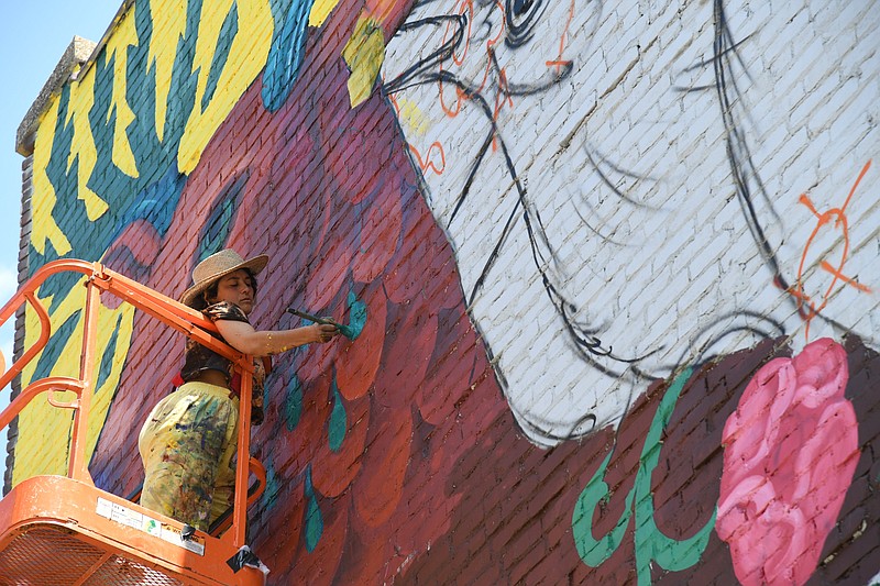 Artist Danaé Brissonnet uses a boom lift to paint the upper part of a new mural at 110 Central Ave. - Photo by Tanner Newton of The Sentinel-Record