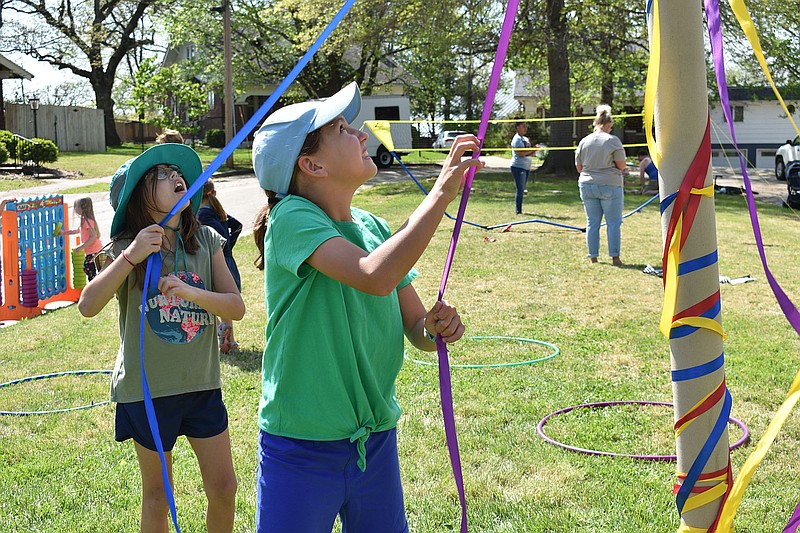 From left, Alex and Norah Coats, ages 9 and 10, play at the maypole Sunday, May 1, 2022, during Porchfest JCMO. (Gerry Tritz/News Tribune photo)