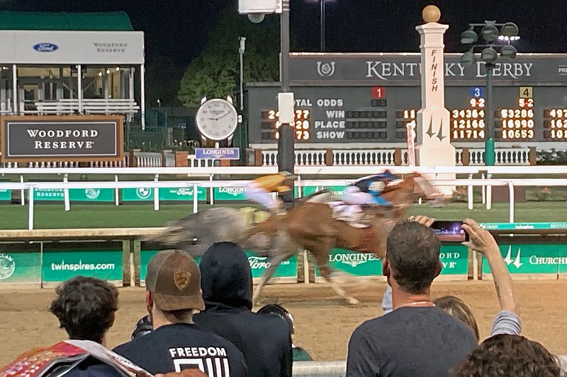 Spectators look on as horses approach the finish of a race at Churchill Downs in Louisville, Ky., Saturday, April 30, 2022. After the COVID-postponed 2020 race was run on Labor Day without spectators and went off last May with limited capacity, the Kentucky Derby could go off with full capacity at Churchill Downs. (AP Photo/Gary Graves)