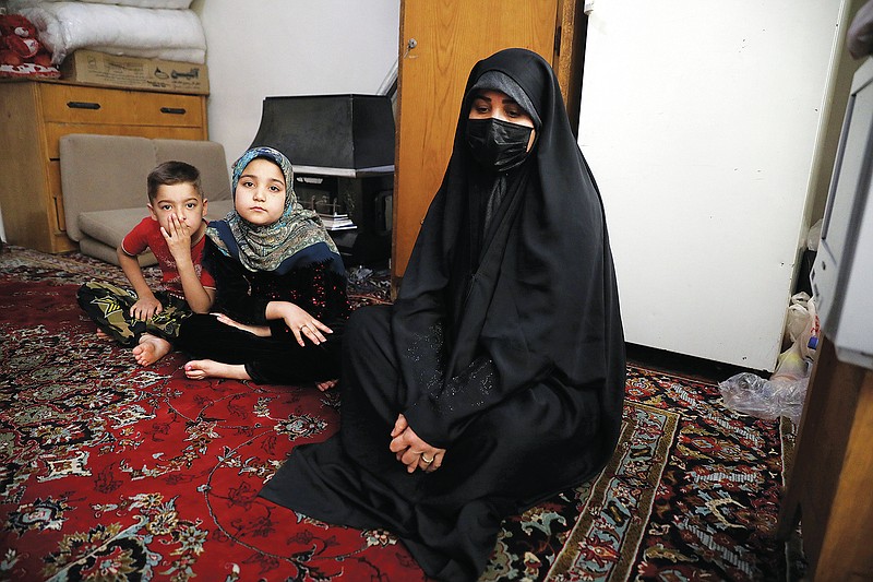 Afghan refugee Zahra Husseini and her children Salehe, center, and Shahrzad sit in their room in a poor suburb of Tehran, Iran, April 21, 2022. The Taliban members who killed her activist husband offered Husseini a deal: Marry one of us, and you'll be safe. Husseini, 31, decided to flee to Iran. (AP Photo/Vahid Salemi)