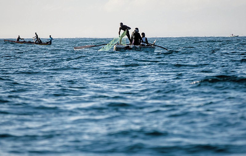 A fisherman pulls his net back onto his boat in the waters surrounding Cap-Haitien, Haiti, Friday, March 11, 2022. A prize winning marine biologist is working to bring together fishermen from Haiti and the Dominican Republic and find a solution that will not only save their livelihoods but also vital marine resources in a region under extreme pressures from climate change. (AP Photo/Odelyn Joseph)