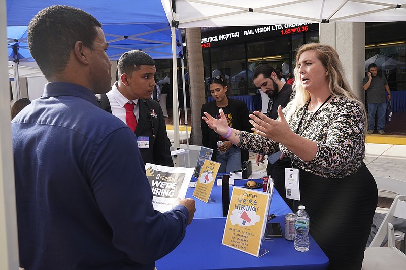 Brittany Dotson explains job opportunities at 0 Percent to job seekers at the Venture Miami Tech Hiring Fair Thursday, April 14, 2022, in Miami.  America’s employers added 428,000 jobs in April, extending a streak of solid hiring that has defied punishing inflation, chronic supply shortages, the Russian war against Ukraine and much higher borrowing costs.  (AP Photo/Marta Lavandier)