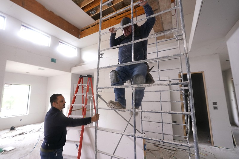 Joshua Correa, left, steadies a scaffolding for Samuel as they work at a home under construction in Plano, Texas, Tuesday, May 3, 2022. There are an estimated 2 million fewer immigrants than expected in the United States, helping fuel a desperate scramble for workers in many sectors, from meatpacking to homebuilding, that are also contributing to shortages and price increases. Correa has struggled to hire supervisors for his work sites, with immigrant job candidates demanding $100,000 yearly pay. (AP Photo/LM Otero)