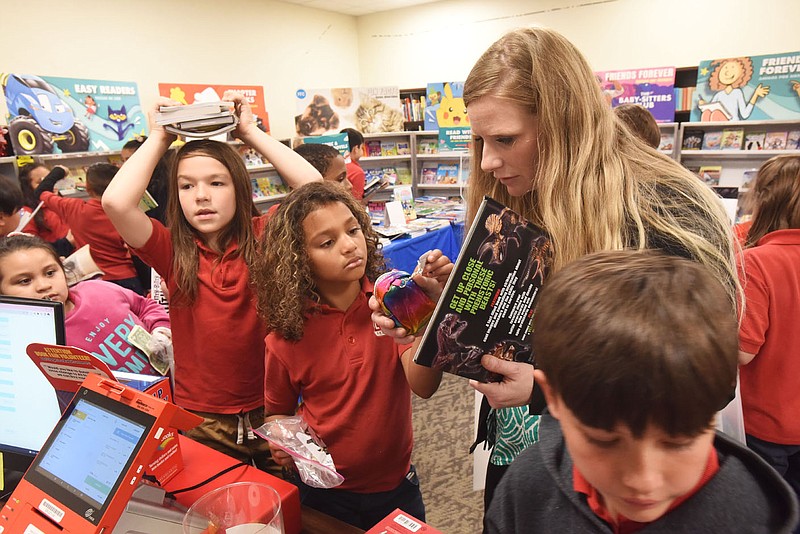 Summer Lunsford, a teacher at Lisa Academy in Springdale, helps students on Tuesday May 3 2022 select books at the school's book fair. Lisa Academy plans to open a school in Rogers this fall.
(NWA Democrat-Gazette/Flip Putthoff)