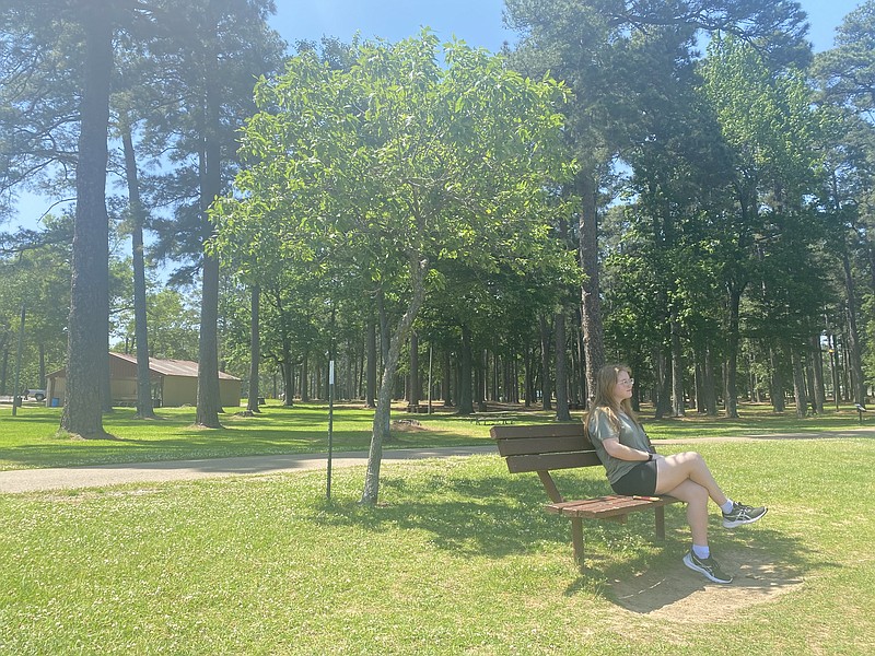 A small tree provides a bit of shade from the sun for Cadyn Cox on a warm afternoon Wednesday, May 11, 2022, at Spring Lake Park in Texarkana, Texas. (Staff photo by Andrew Bell)