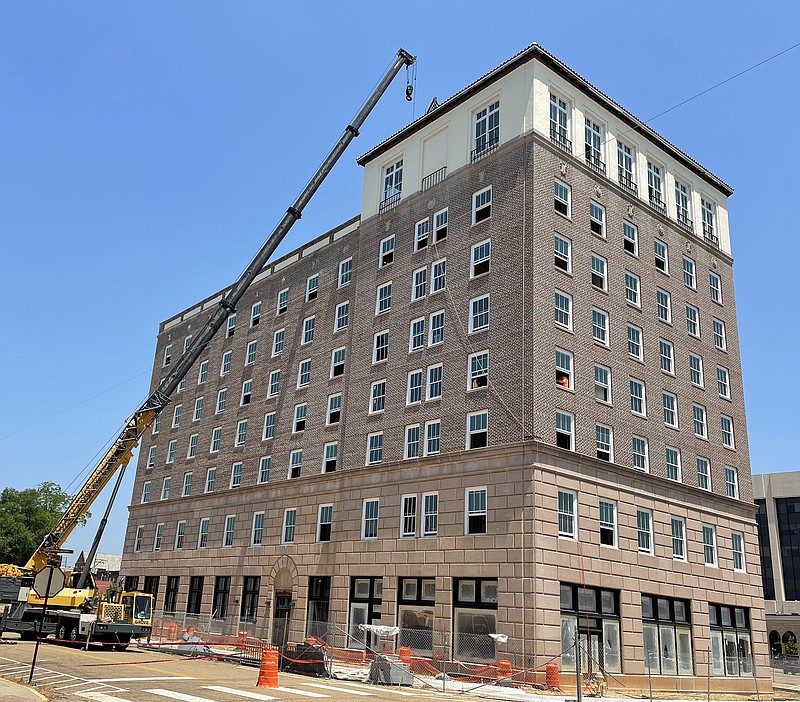 A crane lifts construction materials onto the roof of the Hotel Grim on Thursday in Texarkana, Texas. Work converting the derelict hotel into an apartment building began in November 2019, and the initial estimate for a completion date was spring 2021. The COVID-19 pandemic, an unexpectedly labor-intensive clean-out and hazardous materials abatement process, and surprise foundation problems have all lengthened the project’s timetable. The contractor's latest estimate of an opening date is this fall. (Staff photo by Karl Richter)