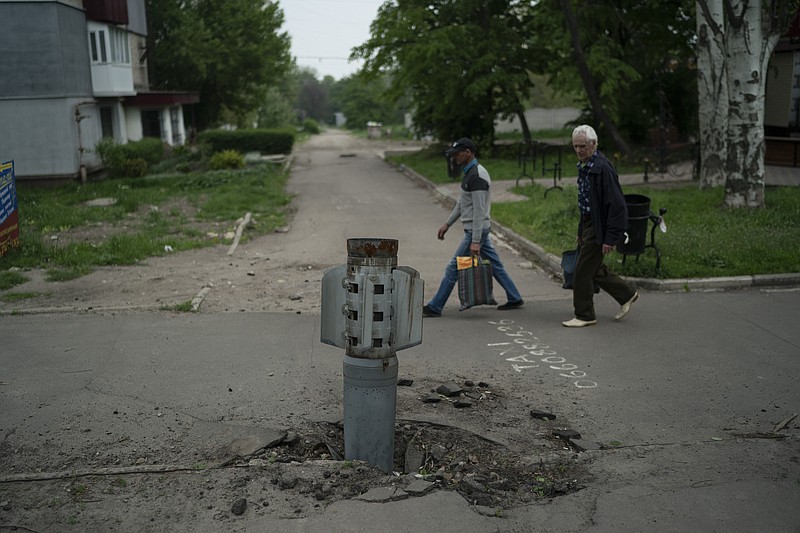 The Associated Press
People walk past part of a rocket that sits wedged in the ground in Lysychansk, Luhansk region, Ukraine, on Friday.