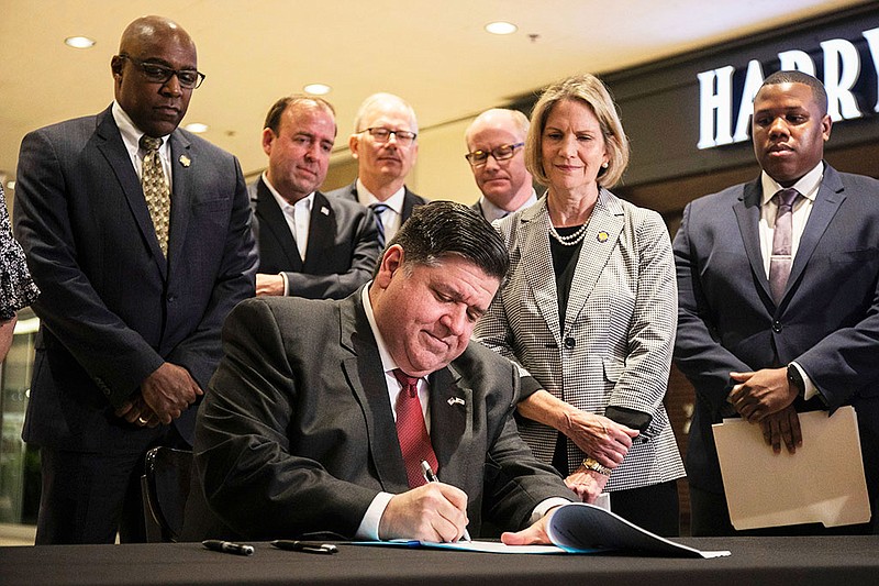 Gov. J.B. Pritzker signs into law a bill that targets organized retail theft as state and city officials watch at the Water Tower Place in the Gold Coast neighborhood of Chicago, Friday, May 13, 2022. Large-scale smash-and-grab crime exploded to the top of the legislative priority list with high-profile cases in Chicago, various California locales and Minneapolis. Gangs enter stores and in a coordinated fashion, break display cases, sweep up merchandise and run. (Pat Nabong/Chicago Sun-Times via AP)