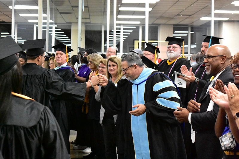 Southeast Arkansas College President Steven Bloomberg fist-bumps a graduate as college officials and board members form a congratulatory line at the end of graduation Friday, May 13, 2022, at the Pine Bluff Convention Center. (Pine Bluff Commercial/I.C. Murrell)