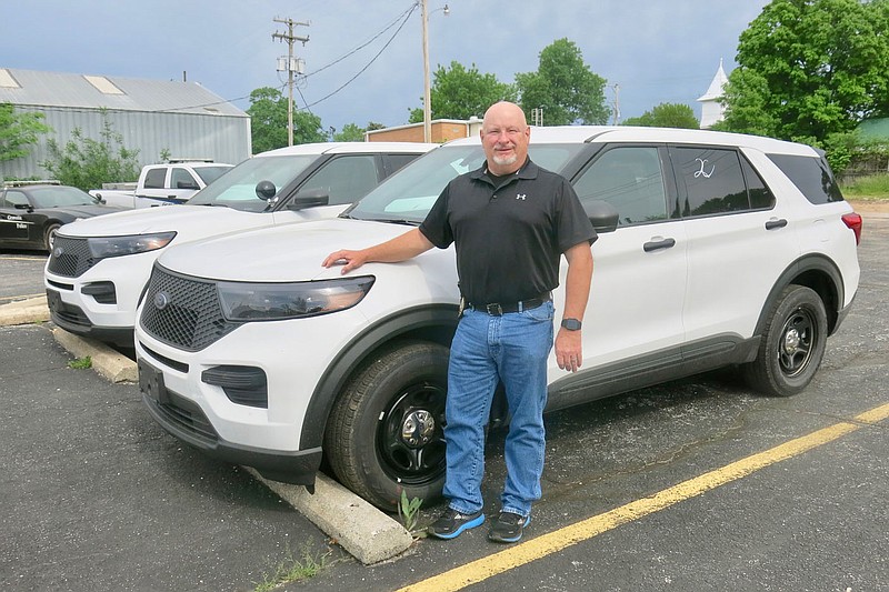 Westside Eagle Observer/SUSAN HOLLAND
Gravette police chief Chuck Skaggs poses with the two new police cruisers recently purchased for the city of Gravette. Skaggs told council members at the May 12 Committee of the Whole meeting that the vehicles would soon be outfitted and ready for the road. He thanked them for approving the purchase.