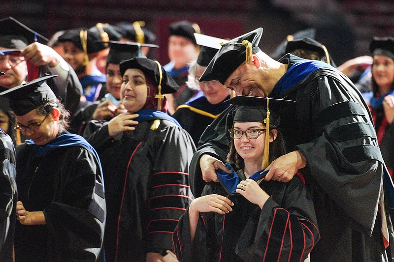 Alison Ramser and other students receive their doctoral hoods on Saturday, May 14, 2022, at the University of Arkansas' main commencement ceremony inside Bud Walton Arena in Fayetteville. The event, at which only graduate students were recognized, including Ramser, who earned a Doctor of Philosophy in cell and molecular biology, was one of several commencements that took place over the weekend at the university. Visit nwaonline.com/220515Daily/ for today's photo gallery.
(NWA Democrat-Gazette/Hank Layton)