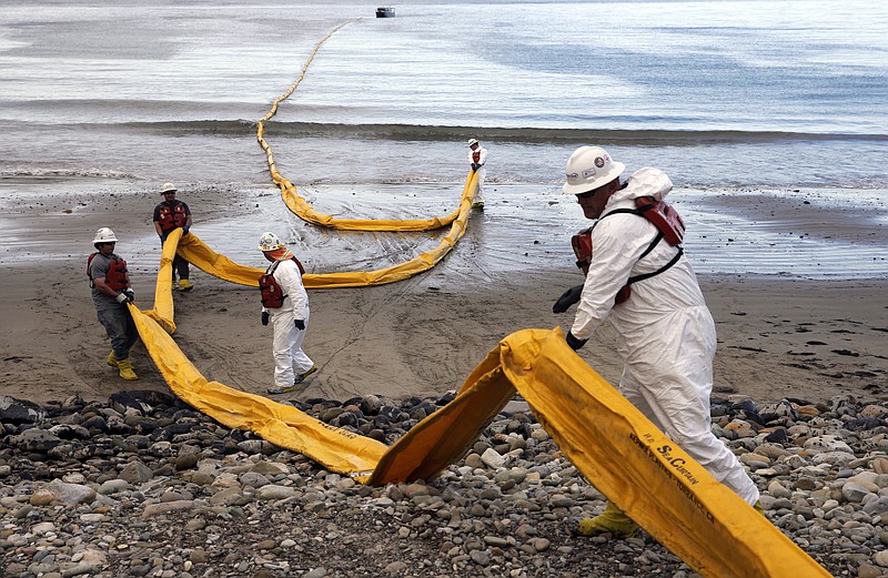 FILE - Workers prepare an oil containment boom at Refugio State Beach, north of Goleta, Calif., on May 21, 2015, two days after an oil pipeline ruptured, polluting beaches and killing hundreds of birds and marine mammals. The owner of an oil pipeline that spewed thousands of barrels of crude oil onto Southern California beaches in 2015 has agreed to pay $230 million to settle a class-action lawsuit by fishermen and property owners, court documents showed Friday, May 13, 2022. (AP Photo/Jae C. Hong, File)