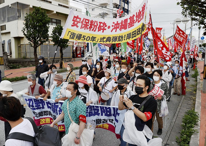 Protesters march, opposing to the ceremony marking the 50th anniversary of its return to Japan after 27 years of American rule on May 15, 1972,  in Ginowan, Okinawa, Sunday, May 15, 2022. Protesters staged a rally demanding a speedier reduction of U.S. military forces.(Kyodo News via AP)