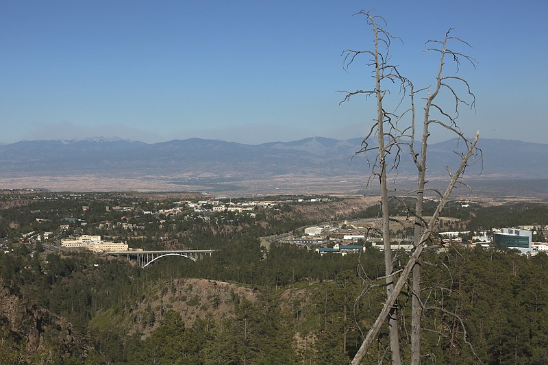 A haze of wildfire smoke hangs over the Upper Rio Grande valley behind the mesa-top city of Los Alamos, N.M., on Thursday, May 12, 2022. Public schools and many businesses were closed as a wildfire crept closer to the city and companion national security laboratory. Scientists at Los Alamos National Laboratory are using supercomputers and ingenuity to improve wildfire forecasting and forest management amid drought and climate change in the American West. (AP Photo/Morgan Lee)