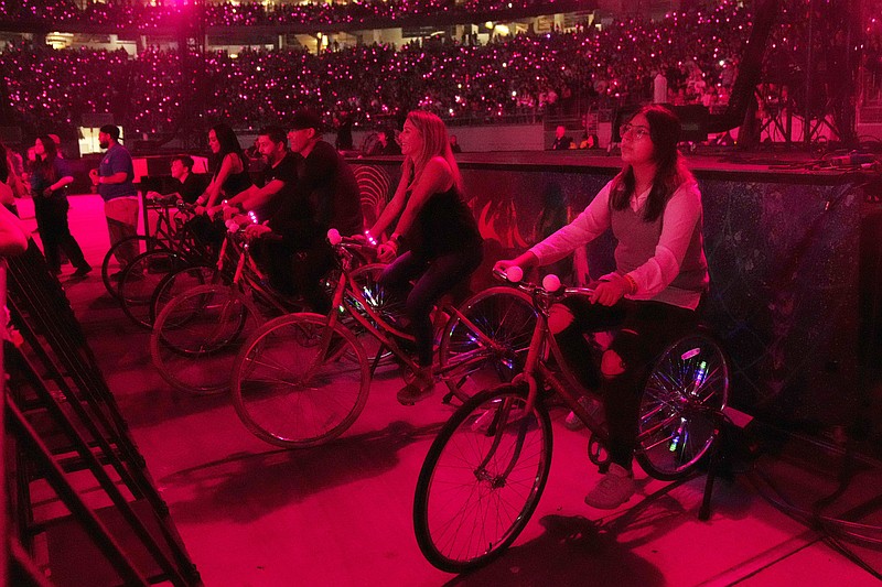 Concertgoers ride stationary bikes during Coldplay's Music of the Spheres world tour on Thursday, May 12, 2022, at State Farm Stadium in Glendale, Ariz. The band has included energy-storing stationary bikes to their latest world tour, encouraging fans to help power the show as part of a push to make the tour more environmentally friendly. (Photo by Rick Scuteri/Invision/AP)