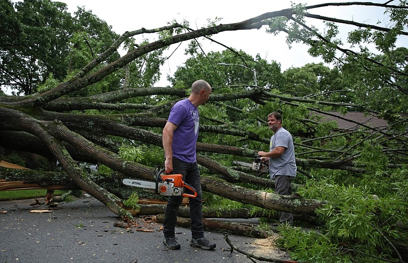 Michael Compton (right) and Joey Piwetz use chainsaws to remove parts of a tree on Cedar Creek Road in North Little Rock after severe weather caused the tree to fall across the street Sunday, May 15, 2022. No injuries were reported at the scene. (Arkansas Democrat-Gazette/Colin Murphey)