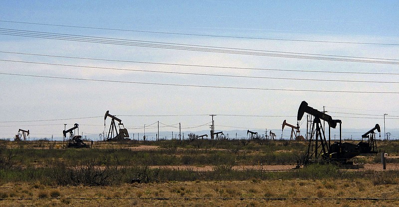 FILE - Oil rigs stand in the Loco Hills field along U.S. Highway 82 in Eddy County, near Artesia, N.M., one of the most active regions of the Permian Basin. Government budgets are booming in New Mexico. The reason behind the spending spree — oil. New Mexico is the No. 2 crude oil producer among U.S. states and the top recipient of U.S. disbursements for fossil fuel production on federal land. But a budget flush with petroleum cash has a side effect: It also puts the spotlight on how difficult it is for New Mexico and other states to turn their rhetoric on tackling climate change into reality. (AP Photo/Jeri Clausing, File)