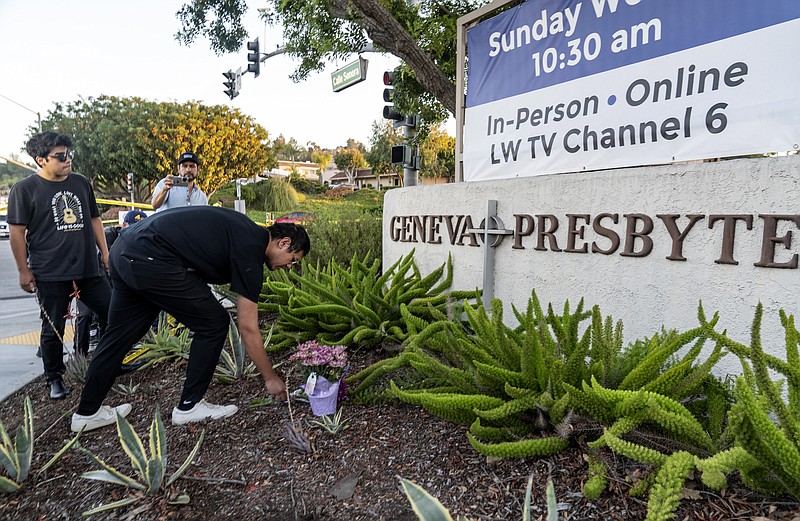 Hector Gomez, left, and Jordi Poblete, worship leaders at the Mariners Church Irvine, leave flowers outside the Geneva Presbyterian Church in Laguna Woods, Calif., Sunday, May 15, 2022, after a fatal shooting. (AP Photo/Damian Dovarganes)