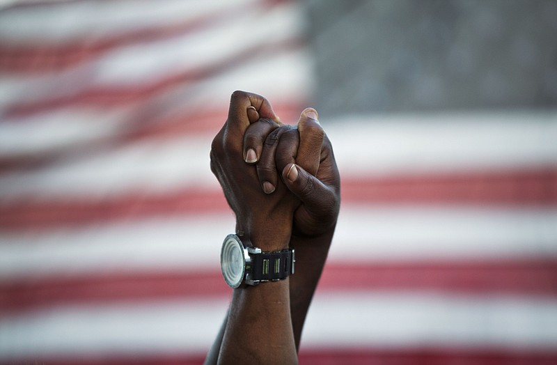 FILE - People join hands against the backdrop of an American flag on June, 21, 2015, as thousands of marchers meet in the middle of Charleston's main bridge in a show of unity after nine black church parishioners were killed by Dylann Roof during a Bible study, in Charleston, S.C. For many Black Americans, the shooting at a supermarket on Saturday, May 14, 2022, in Buffalo, New York, has stirred up the same feelings they faced after Charleston and other attacks: the fear, the vulnerability, the worry that nothing will be done politically or otherwise to prevent the next act of targeted racial violence. (AP Photo/David Goldman, File)