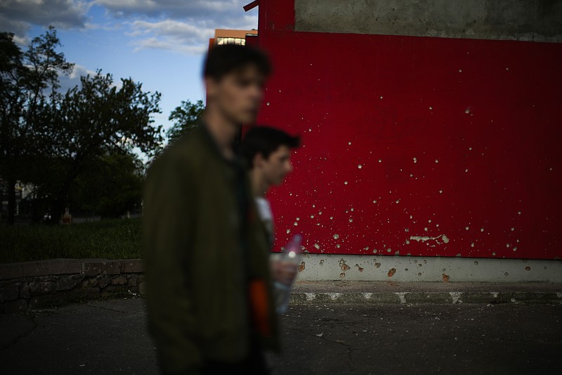 Youngsters walk past a wall scarred by shrapnel after a bombing earlier in the day in Mykolaiv, Ukraine, Monday, May 16, 2022. (AP Photo/Francisco Seco)